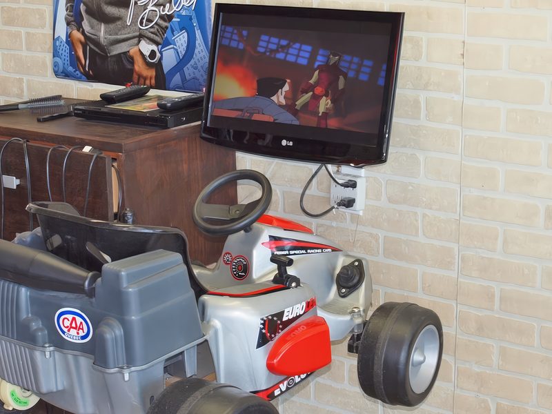 Kids' car-shaped chair facing a TV playing cartoons
